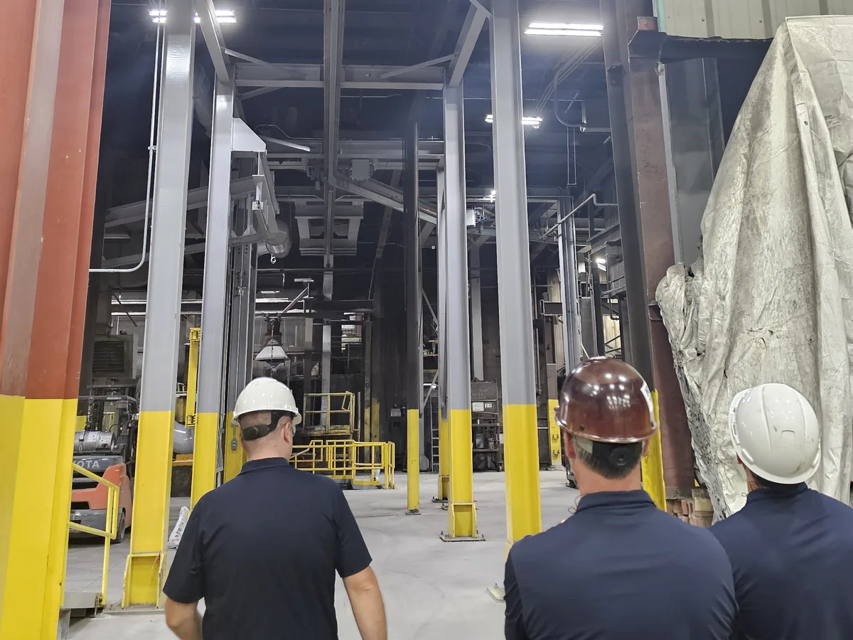 Three GIP engineers in hard hats walking a plant floor between structural columns