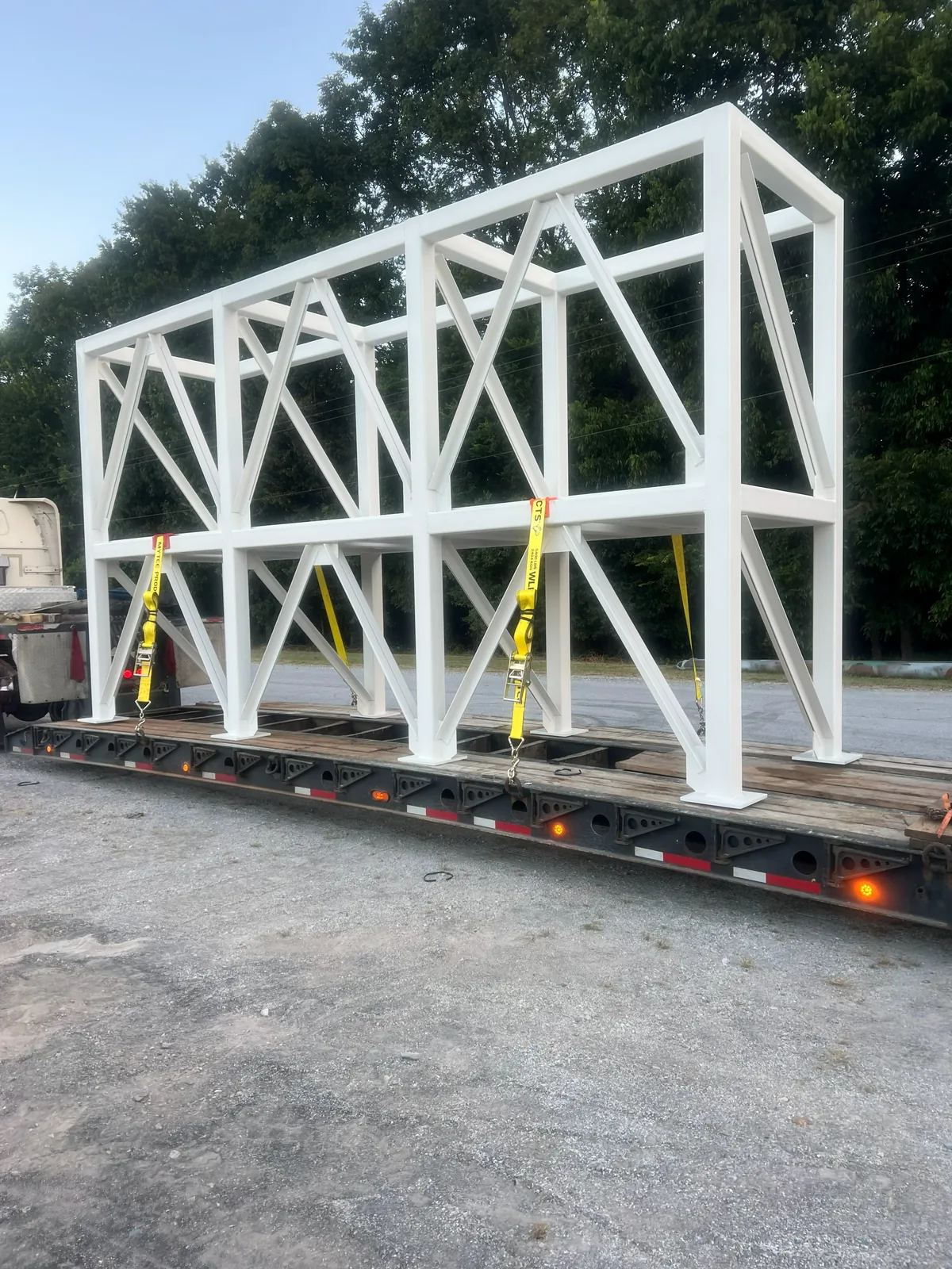 Painted braced steel frame chained to a lowboy trailer for delivery