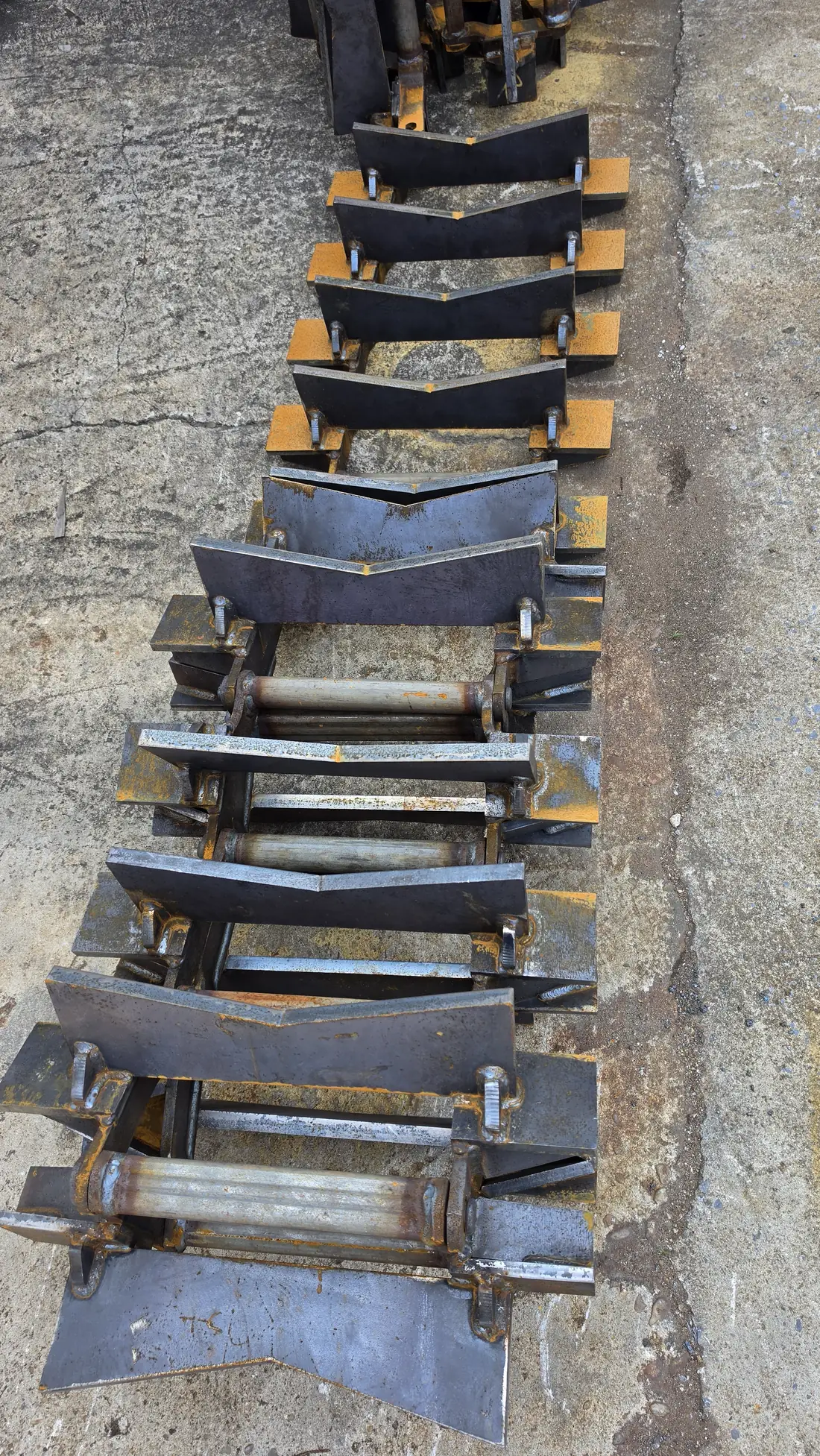 Fabricated axial conveyor chain links and flights laid out on the shop floor for inspection