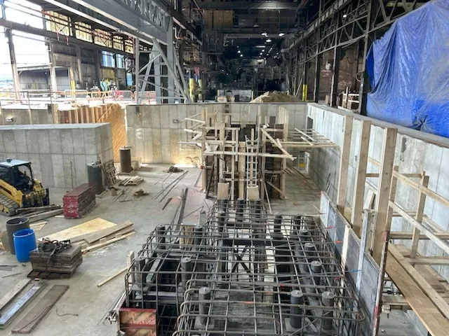 Reinforcing cages with anchor bolt sleeves set inside a pit before the pour