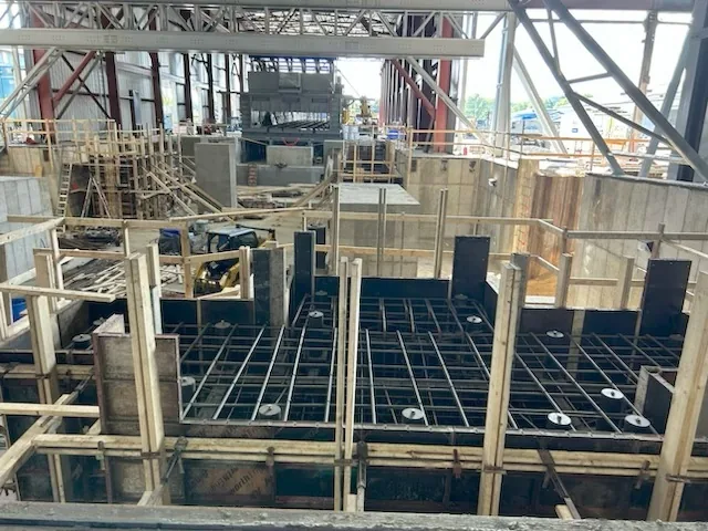 Formwork with embed plates and anchor bolts set on the top mat inside a mill building