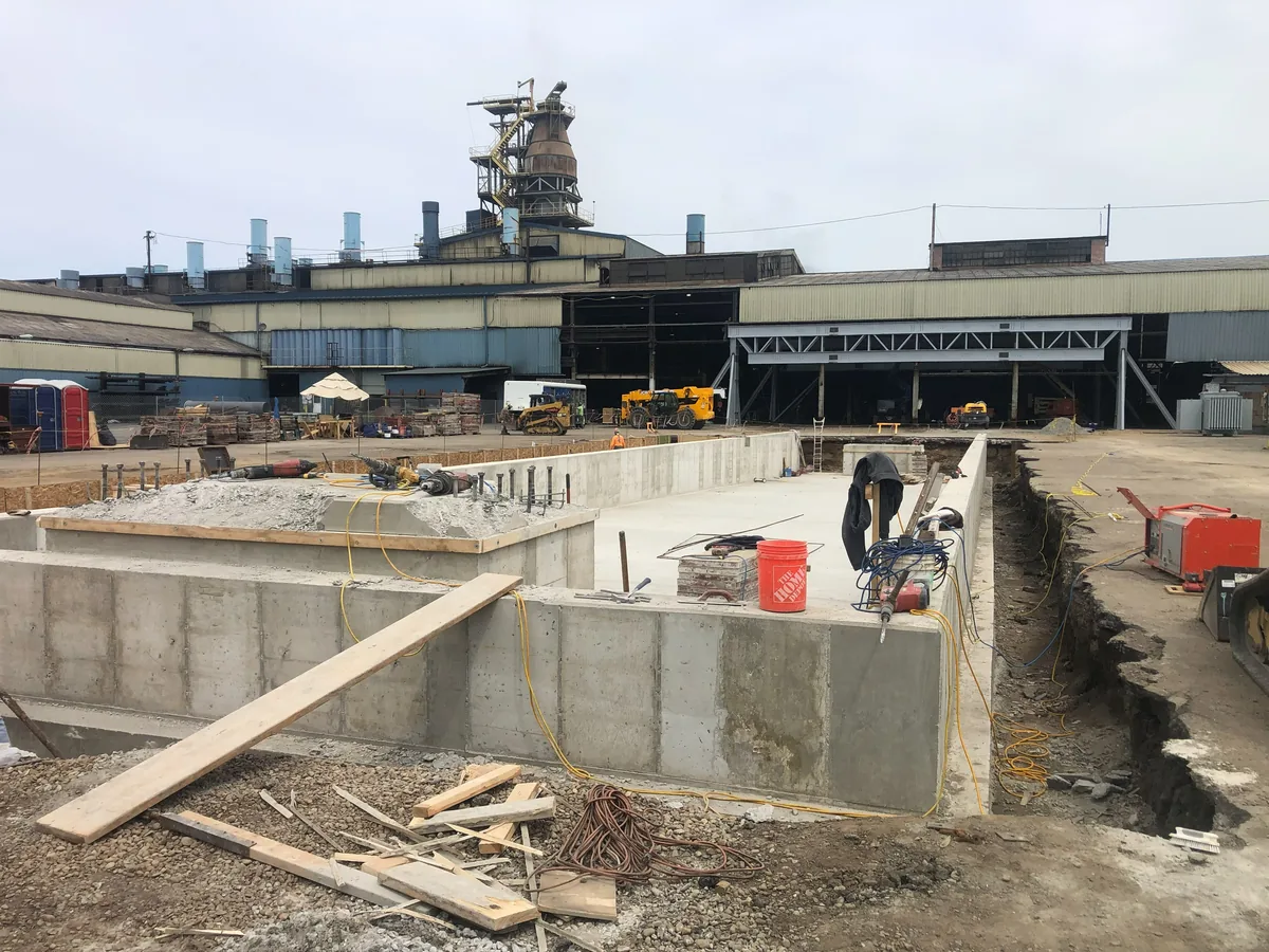 Cast-in-place equipment pit walls and piers outside a mill building