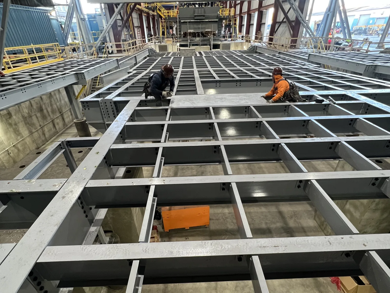 Crew installing a steel mezzanine grid inside an industrial facility
