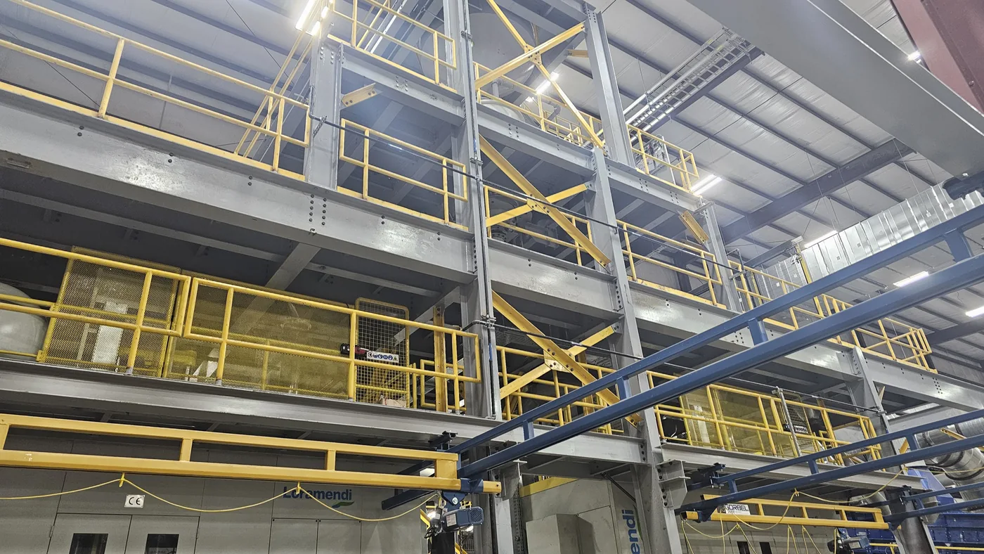 Steel equipment mezzanine with handrail and stairs over process equipment